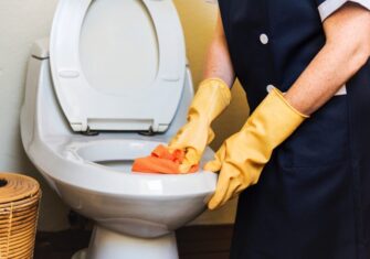 Janitor cleaning a business toilet with a sponge Janitorial Services: Top 5 Ways Your Business Can Benefit From Them