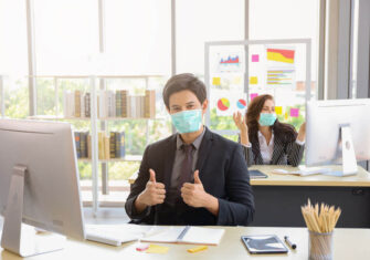 Man at desk wearing a mask Reopening for Business: 7 Best Practices to Mitigate Fear