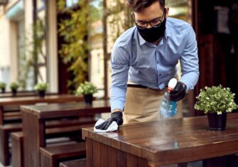 Waiter disinfecting a table at a restaurant Show Your Restaurant Some Love This Valentine's Day with These Disinfecting Tips