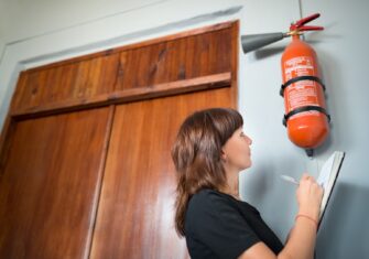 Someone checking a fire extinguisher 4 Tips for Fire and Safety System Maintenance