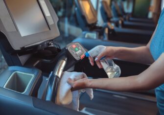 Person spraying disinfectant on a treadmill The Importance of Cleaning Fitness Equipment at Your Athletic Facility