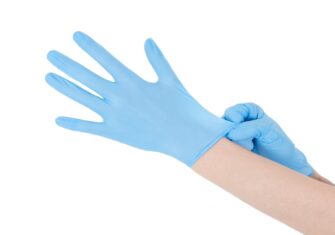 Person putting on reusable vinyl gloves The Right Way to Use Reusable Vinyl Gloves so You Can Stay Sanitary and Save Money as You Re-open