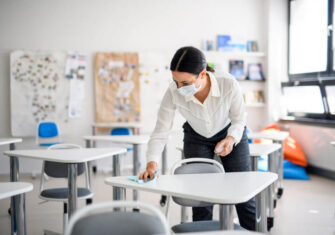 Woman disinfecting a school desk CARES Act - How Do Schools Benefit?