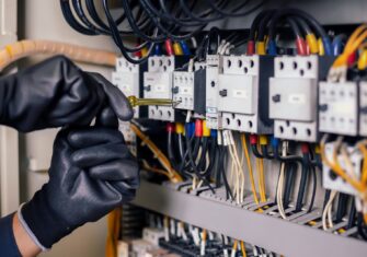 Contractor maintaining electrical sockets How Electrical Maintenance Can Affect Your Bottom Line