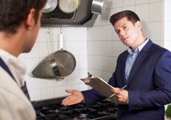 Health inspector looking at kitchen commercial floor Top 5 Services You Need to Ensure Your Restaurant Is Health Department Compliant