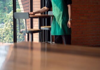 Busser cleaning restaurant table How to Implement Green Cleaning into Your Restaurant to Keep Food and People Safe