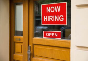 "Now Hiring" sign on a door How to Navigate the Current Labor Shortage in Your Industry