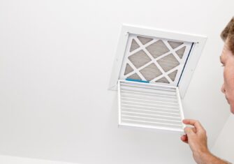 Guy inspecting an air vent How to Manage Your Indoor Air Quality in a Busy Facility