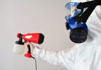 Person in suit disinfecting a facility. How Disinfection Misting Can Help You Combat Flu Season and Reduce Labor Costs