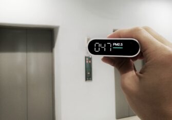 Hand holding up an alarm clock in a commercial building. Areas to Focus on Indoor Air Quality in Your Commercial Building