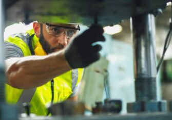 Contractor working in a factory. The Vital Role of Maintenance Services in Avoiding Production Downtime