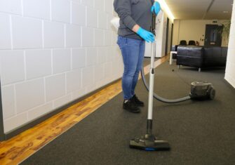 Woman cleaning a carpet. Why Common Periodic Carpet Cleaning Services Are Best for Employee Health